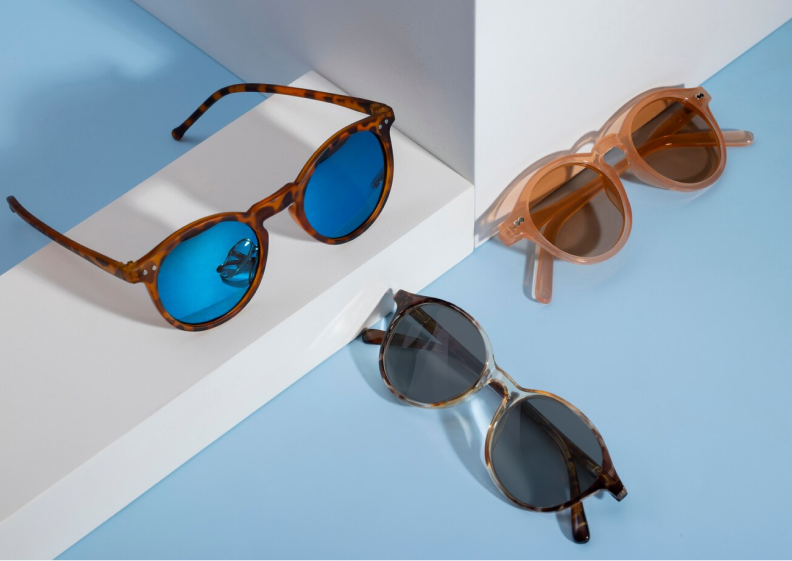 Sunglasses and eyeglasses displayed on a blue background